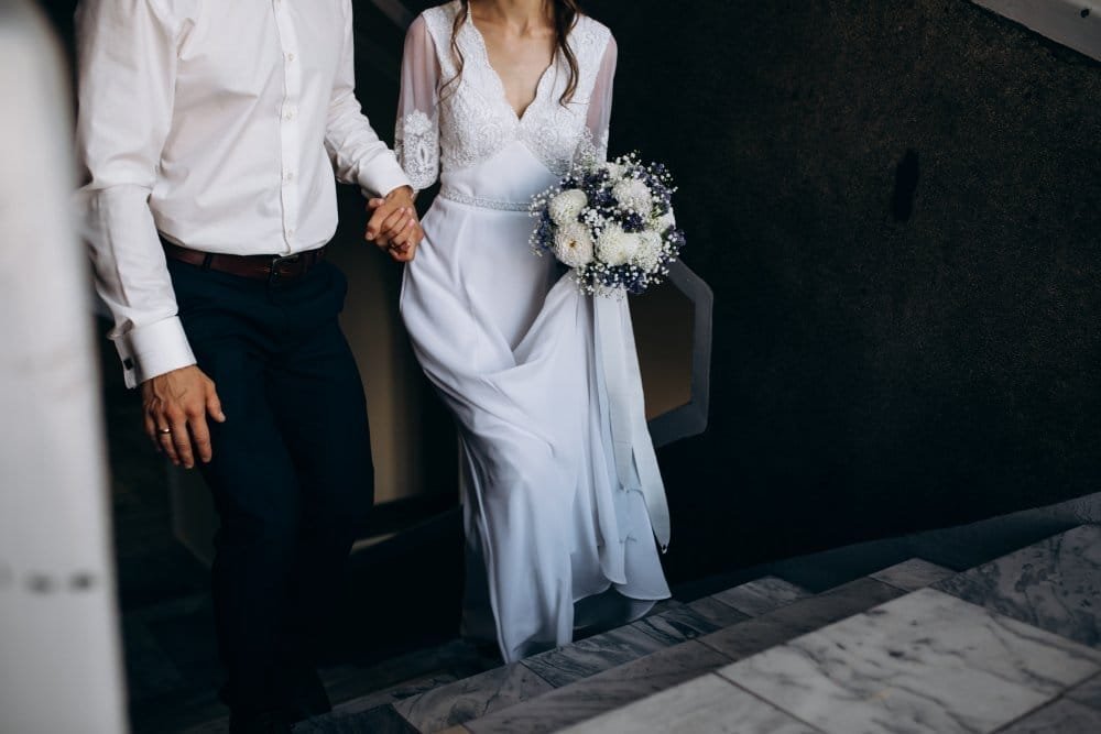 groom holds bride s hand while they go upstairs