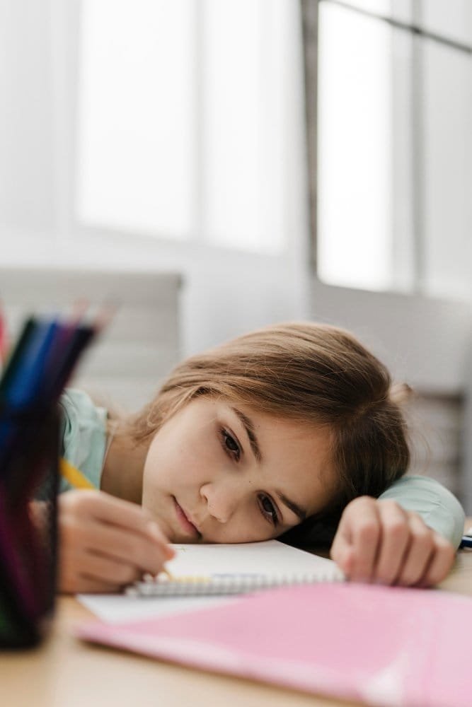little girl taking notes while being bored